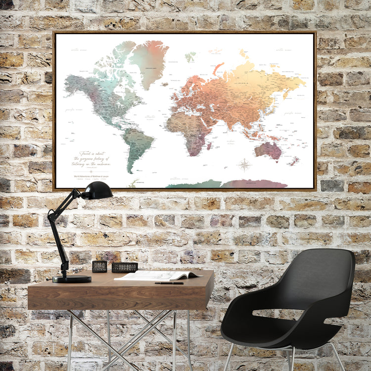 a large world map hanging on a brick wall above a wooden desk with a black desk lamp and a black chair.