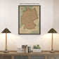 a framed map of Germany hanging on a wall, with two lamps on a shelf below it.