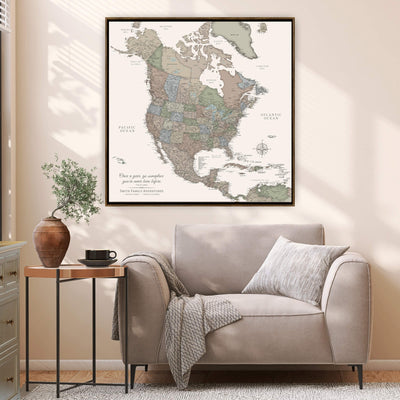 a large framed map of North America hanging on a wall in a living room. The map is surrounded by various decorative elements, including a potted plant, a vase, and a small side table with a coffee cup. The room has a comfortable seating area with a sofa and a chair, creating a cozy and inviting atmosphere.