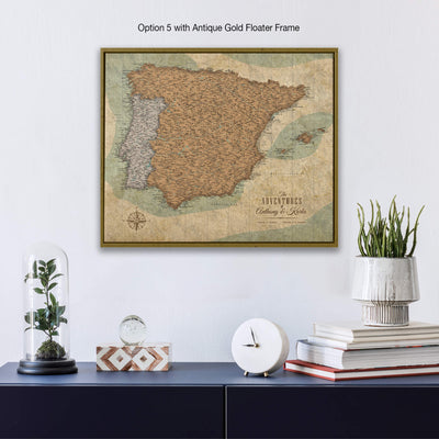 a framed vintage map of Spain hanging on a wall, with a glass dome containing a plant and a stack of books below it.