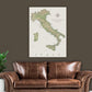 a large map of Italy hanging on a wall above a brown leather couch.