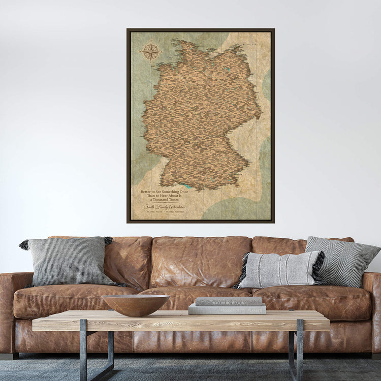 a large map of Germany hanging on a wall above a brown leather couch with pillows.