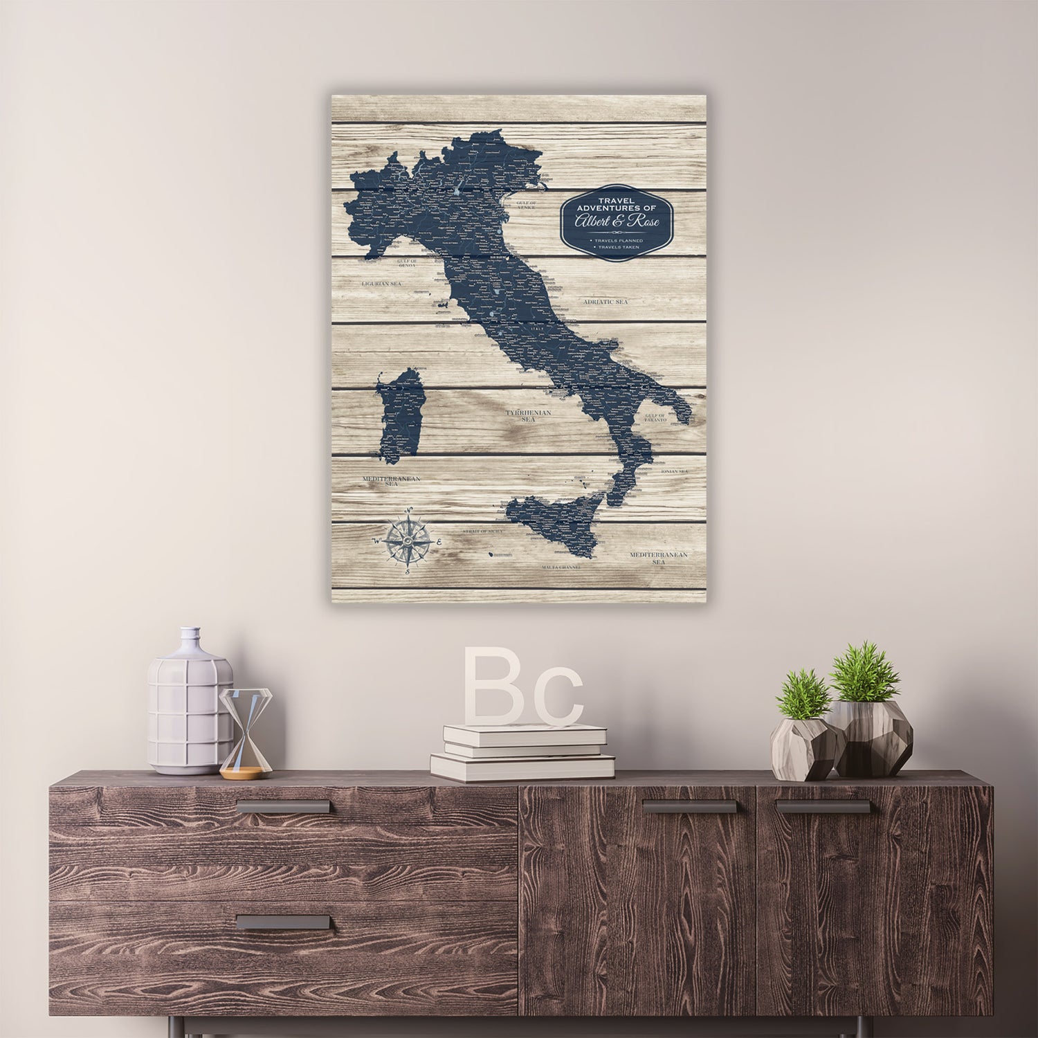 a wooden dresser with a map of Italy hanging on the wall above it. The dresser also has some decorative items on it, such as a bottle, a vase, and a stack of books.