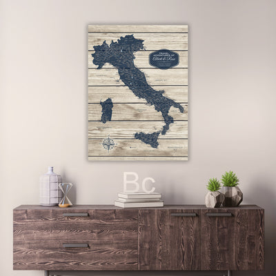 a wooden dresser with a map of Italy hanging on the wall above it. The dresser also has some decorative items on it, such as a bottle, a vase, and a stack of books.