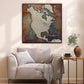 a large, colorful map of North America hanging on a wall above a beige armchair in a cozy living room setting.