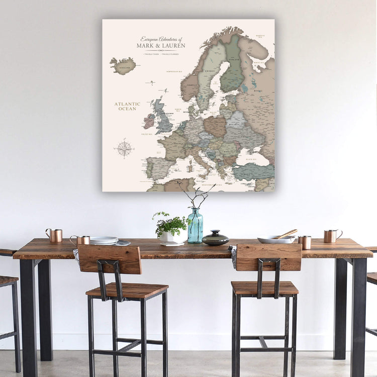 a large map of Europe hanging on a wall above a wooden dining table with chairs.