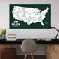a large map of the United States with silhouettes of football players, representing the Big Ten Football Conference. The map is displayed on a wall above a wooden desk with a chair, a lamp, and some books.