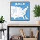 a framed map of the United States with football locations marked, hanging on a wall above a wooden table with various items on it.