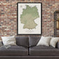 a large map of Germany hanging on a brick wall above a gray couch with white pillows.