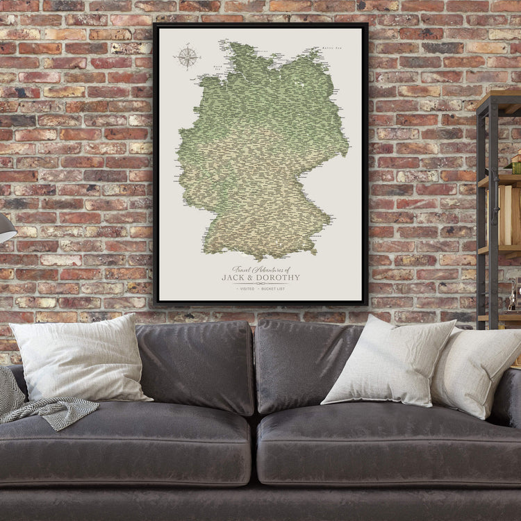 a large map of Germany hanging on a brick wall above a gray couch with white pillows.