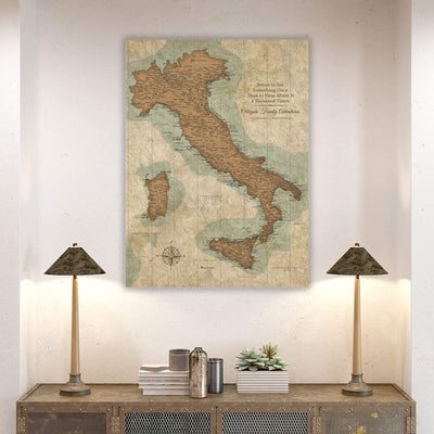 a large map of Italy hanging on a wall, with two lamps on a wooden table below it.