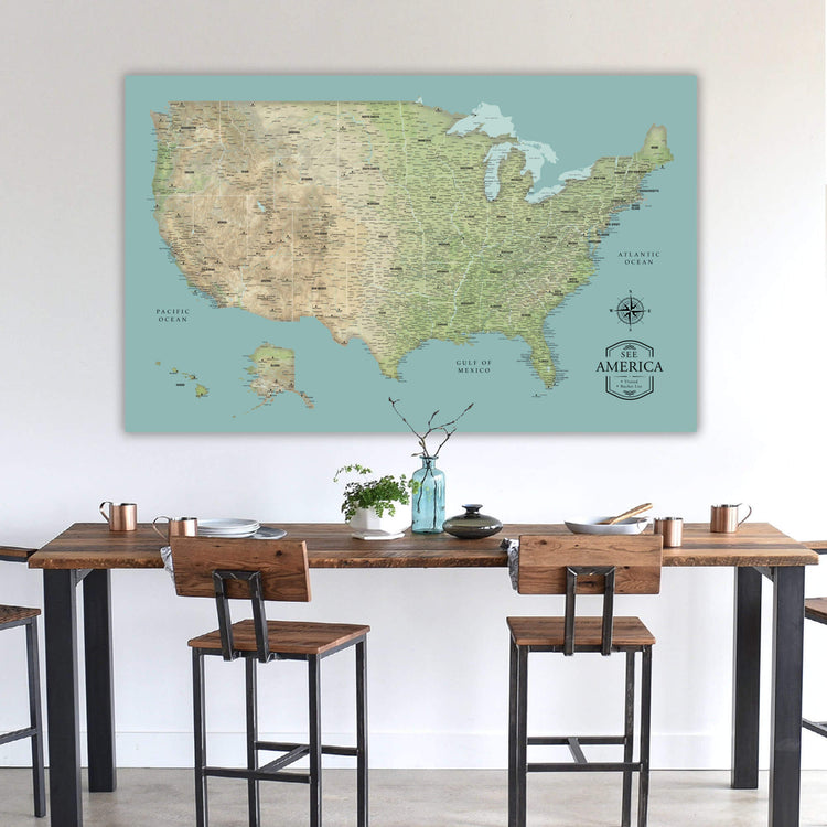 a large map of the United States displayed on a wall above a wooden dining table with chairs.