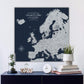 a large map of Europe on a wall, with a glass dome containing a plant and a stack of books on a blue shelf below it.