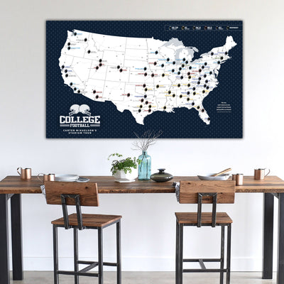 a large map of the United States with various locations marked, displayed on a wall above a wooden dining table with two chairs.