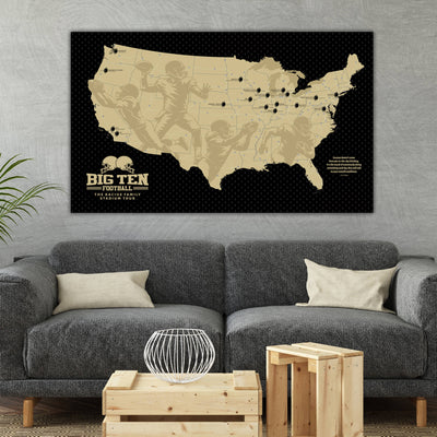 a large black and white map of the United States with football players depicted on it, hanging on a wall above a gray couch and a wooden coffee table.