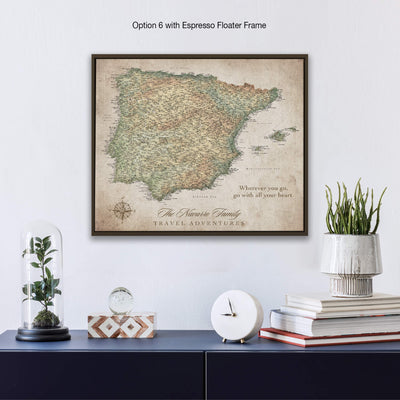 a framed map of Spain hanging on a wall, with a glass dome containing a plant and a stack of books below it.