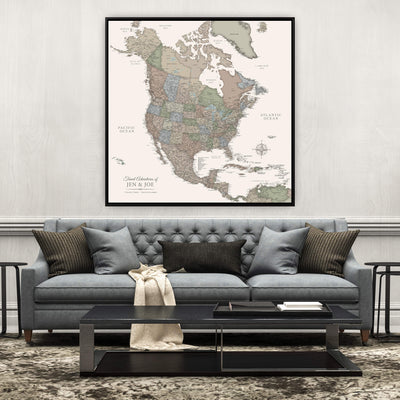 a large, detailed map of North America hanging on a wall above a gray sofa with a black coffee table in front of it.
