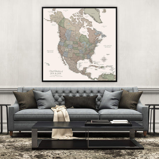 a large, detailed map of North America hanging on a wall above a gray sofa with a black coffee table in front of it.