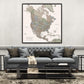 a large, detailed map of North America hanging on a wall above a gray sofa with a black coffee table in front of it.