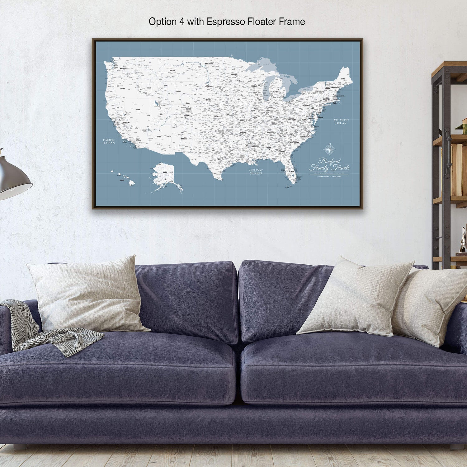a large map of the United States with a blue background and white text, hanging on a wall above a blue couch with pillows.