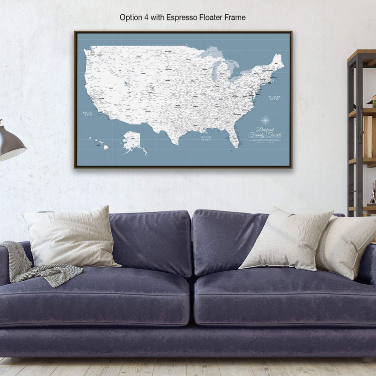 a large map of the United States with a blue background and white text, hanging on a wall above a blue couch with pillows.