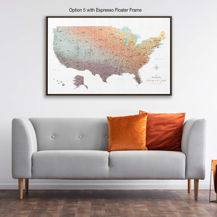 a large framed map of the United States hanging on a wall above a gray sofa with orange and red throw pillows.
