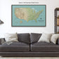 A large framed map of the United States is displayed on the wall above a gray couch with white pillows.