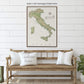 a framed map of Italy hanging on a white wall above a wooden bench with pillows.