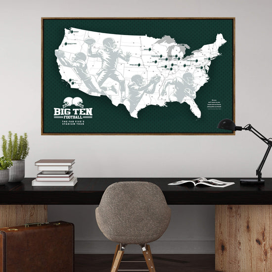 a large framed map of the United States with football players depicted on it, hanging on a wall above a wooden desk with a chair and some books.