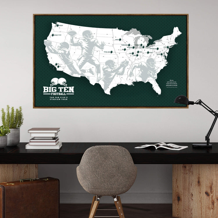 a large framed map of the United States with football players depicted on it, hanging on a wall above a wooden desk with a chair and some books.