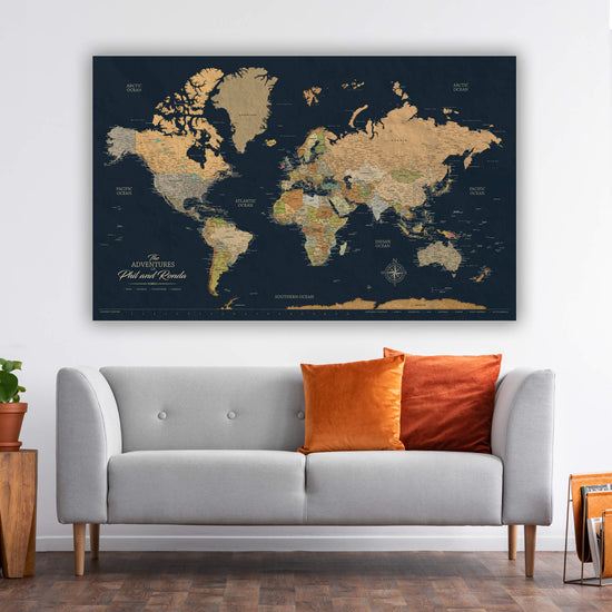 a large world map poster hanging on a wall above a gray sofa with orange and red throw pillows.