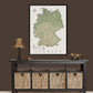 a large framed map of Germany hanging on a wall above a black console table with woven baskets below it.