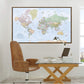 a large world map hanging on a wall above a wooden desk with a laptop, books, and a lamp.