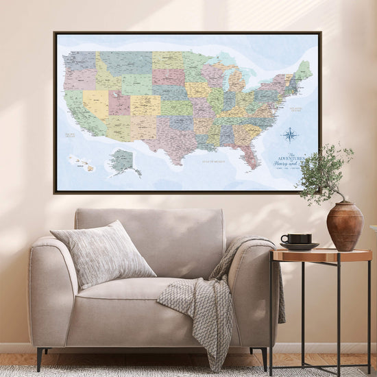 a large, colorful map of the United States hanging on a wall above a beige sofa in a living room.