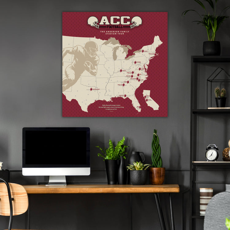a wall-mounted map of the United States with football player locations marked, along with a desk with a computer monitor, keyboard, and potted plants.