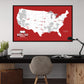 a large framed map of the United States with various locations marked, including a football stadium, against a red background.