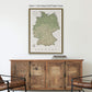 a framed map of Germany hanging on a wall above a wooden cabinet.