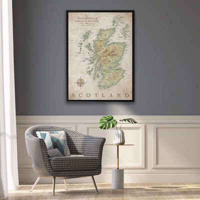 a framed map of Scotland hanging on a wall, with a gray armchair and a small side table with a plant in front of it.