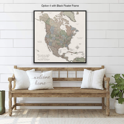a large map of North America with a black frame, hanging on a white wall above a wooden bench with two white pillows.