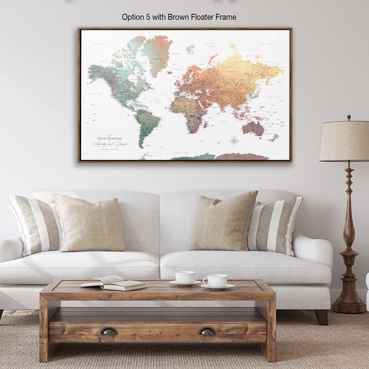a large world map in a brown frame, hanging on a wall above a white couch with a wooden coffee table in front of it.