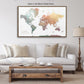 a large world map in a brown frame, hanging on a wall above a white couch with a wooden coffee table in front of it.