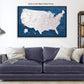 a large, detailed map of the United States displayed on a wall above a blue couch with pillows.