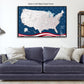 a large, detailed map of the United States with a black float frame, displayed on a wall above a blue couch with pillows.