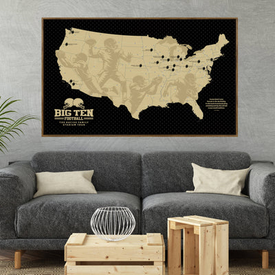 a large framed map of the United States with football players depicted on it, hanging on a wall above a gray couch and a coffee table in a living room setting.