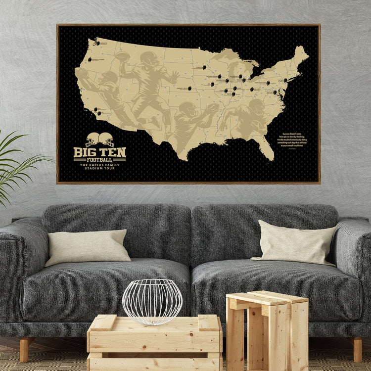 a large framed map of the United States with football players depicted on it, hanging on a wall above a gray couch and a coffee table in a living room setting.