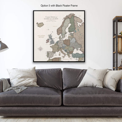 a large framed map of Europe hanging on a wall above a gray couch with white pillows.