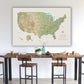 a large map of the United States hanging on a wall above a wooden dining table with chairs.