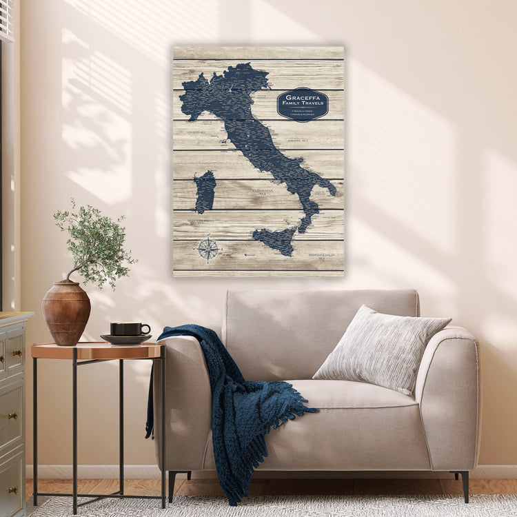 a cozy living room with a comfortable couch, a wooden side table, and a potted plant. Above the couch, there is a large map of Italy hanging on the wall, depicting the country in a unique wooden and blue design.