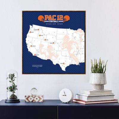 a framed map of the United States with various locations marked, including a football stadium, and the text "PAC 12 Football Stadium Tour" printed on it. Below the map, there is a small glass dome containing a plant, a white clock, and a stack of books.