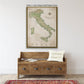 a large framed map of Italy hanging on a wall above a wooden bench with a "welcome home" pillow.